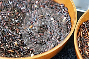 Selected focused of raw brown rice or paddy seed in brown ceramic bowl.