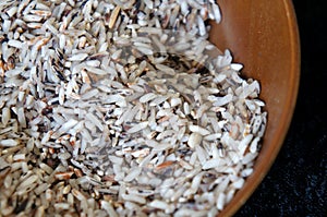 Selected focused of raw brown rice or paddy seed in brown ceramic bowl.