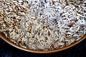 Selected focused of raw brown rice or paddy seed in brown ceramic bowl.