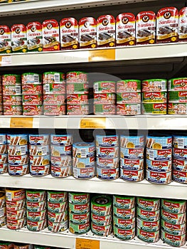 Selected focused on tuna fish fillet in the cans and displayed for sale on shelves in the supermarket.
