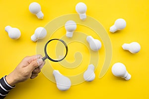 Selected great ideas concepts with male hand using magnifying glass looking for group of lightbulb on color background.Business