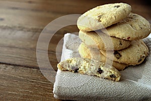 Selection of choc chip and fruit cookies, on a serviette on a wooden table. Copy space for text