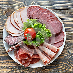 Selection of cold meats, including a variety of processed cold meat products, displayed on a wooden background.