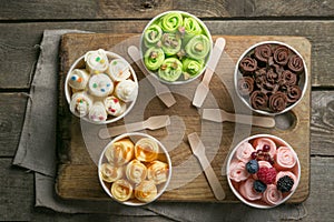 Selection of different rolled ice creams in cone cups photo
