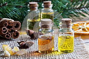Selection of essential oils with star anise, cinnamon, frankincense and pine branches