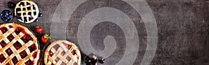 Selection of fresh fruit pies. Above view corner border over a dark stone background with copy space.