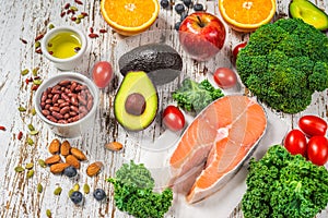 Selection of fresh fruit and vegetables, salmon, beans, and nuts.