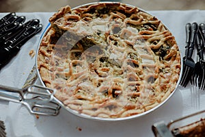 Selection of freshly-baked pies arranged on white paper with knives, ready to be enjoyed