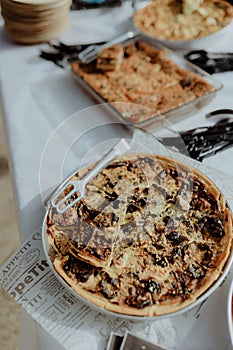 Selection of freshly-baked pies arranged on white paper with knives, ready to be enjoyed