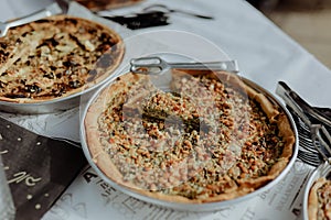 Selection of freshly-baked pies arranged on white paper with knives, ready to be enjoyed