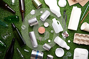 A selection of garbage for recycling. Segregated glass, metal, plastic and paper on green grass background.