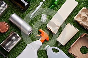 A selection of garbage for recycling. Segregated glass, metal, plastic and paper on green grass background.