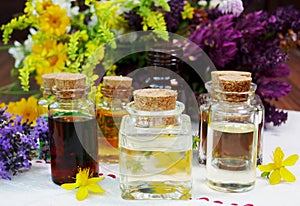 Selection of glass aromatherapy essential oil bottles, with herbs and flowers