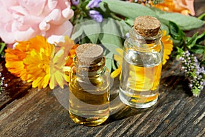 Selection of glass aromatherapy essential oil bottles, with herbs and flowers in the