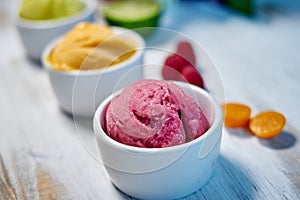 Selection of gourmet flavours of Italian ice cream in vibrant colors served in individual porcelain cups on an old