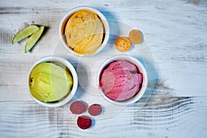 Selection of gourmet flavours of Italian ice cream in vibrant colors served in individual porcelain cups on an old