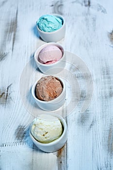 Selection of gourmet flavours of Italian ice cream in vibrant colors served in individual porcelain cups on an old