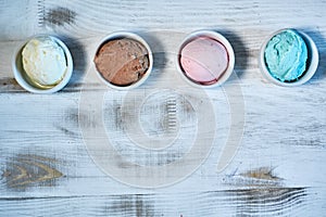 Selection of gourmet flavours of Italian ice cream in vibrant colors served in individual porcelain cups on an old