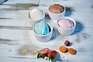 Selection of gourmet flavours of Italian ice cream in vibrant colors served in individual porcelain cups on an old