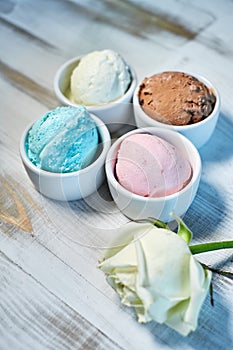 Selection of gourmet flavours of Italian ice cream in vibrant colors served in individual porcelain cups on an old