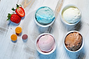 Selection of gourmet flavours of Italian ice cream in vibrant colors served in individual porcelain cups on an old