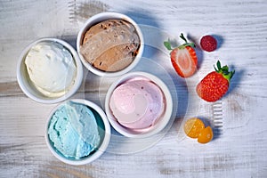 Selection of gourmet flavours of Italian ice cream in vibrant colors served in individual porcelain cups on an old
