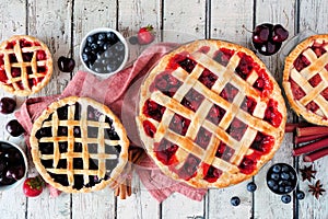 Selection of homemade fruit pies. Above view table scene over rustic white wood.