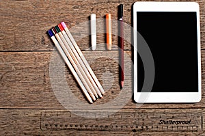 A selection og coloured pencils and a tablet seen from above