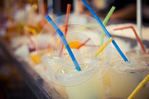 Selection of plastic cups with grapefruit juice and colored straws