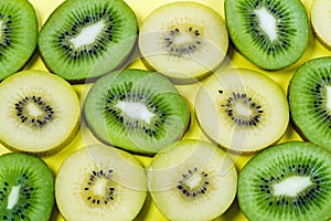 Selection of slices of yellow and green kiwi fruit on a bright high contrast yellow background