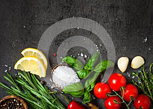 Selection of spices and herbs on dark stone table.