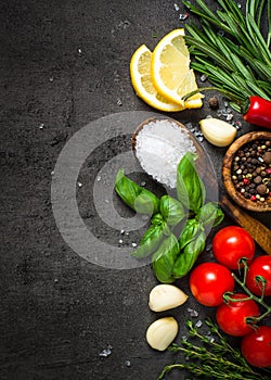 Selection of spices and herbs on dark stone table.