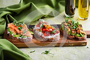 Selection of tasty bruschetta or canapes on taosted baguette and quark cheese topped with smoked salmon, olives, tomato