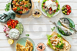 Selection of traditional greek food - salad, meze, pie, fish, tzatziki, dolma on wood background