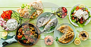Selection of traditional greek food - salad, meze, pie, fish, tzatziki, dolma on wood background