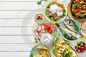 Selection of traditional greek food - salad, meze, pie, fish, tzatziki, dolma on wood background