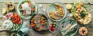 Selection of traditional greek food - salad, meze, pie, fish, tzatziki, dolma on wood background