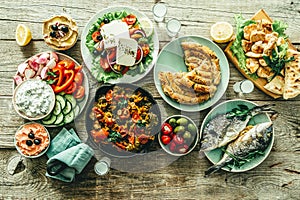 Selection of traditional greek food - salad, meze, pie, fish, tzatziki, dolma on wood background