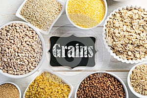 Selection of whole grains in white bowls - rice, oats, buckwheat, bulgur, porridge, barley, quinoa, amaranth,