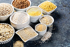 Selection of whole grains in white bowls - rice, oats, buckwheat, bulgur, porridge, barley, quinoa, amaranth