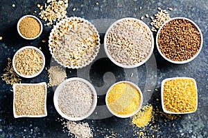 Selection of whole grains in white bowls - rice, oats, buckwheat, bulgur, porridge, barley, quinoa, amaranth