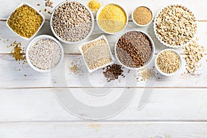 Selection of whole grains in white bowls - rice, oats, buckwheat, bulgur, porridge, barley, quinoa, amaranth,