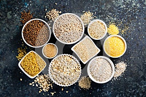 Selection of whole grains in white bowls - rice, oats, buckwheat, bulgur, porridge, barley, quinoa, amaranth