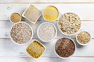 Selection of whole grains in white bowls - rice, oats, buckwheat, bulgur, porridge, barley, quinoa, amaranth,