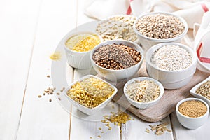 Selection of whole grains in white bowls - rice, oats, buckwheat, bulgur, porridge, barley, quinoa, amaranth, photo
