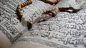 Selectiv focus of tasbih on the old Koran & x28;the Quran uses the arob language& x29; in a dim and solemn light