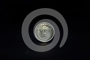 Selective blur on a 250 rials coin from Iran, isolated on a black background. IRR, or iranian rial, is the official currency and