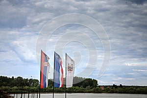 Selective blur on the Flags of Serbia and Sabac in front of the sava river and a cloudy sky. Sabac is a serbian city in the macva