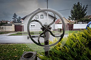 Selective blur on a manual water pump, an old public fountain with its tap faucet, pumping water from a well, for communal use, in