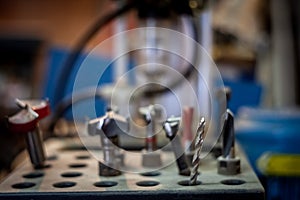 Selective blur on several drills used for woodworking in a carpenter workshop, in the middle of other components and parts used